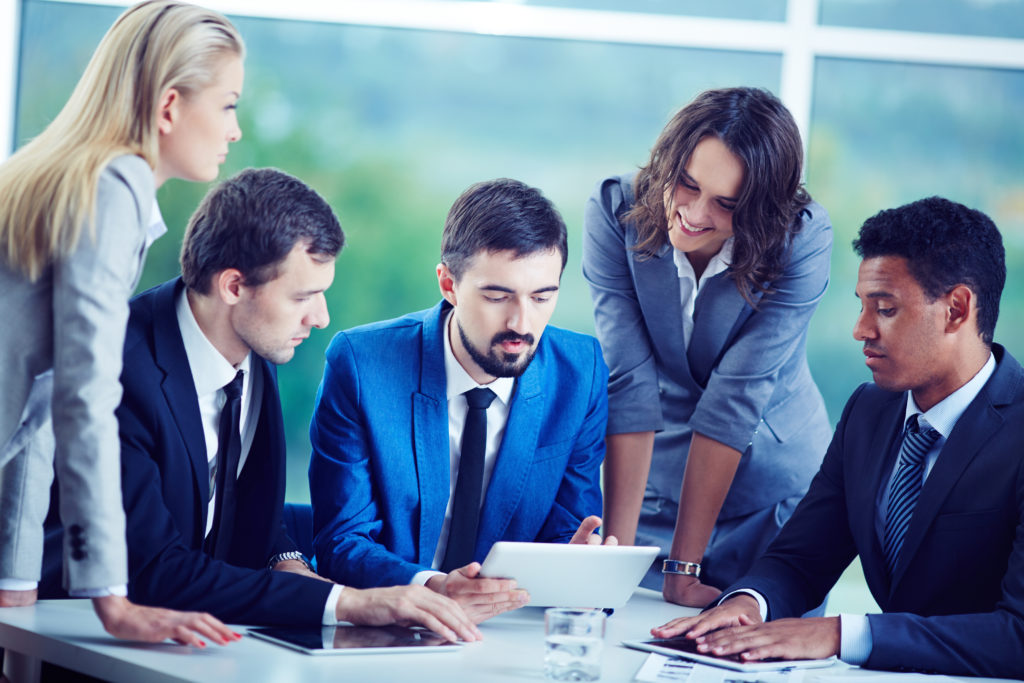 Business executives analyzing IT data and strategy during a corporate meeting with a digital tablet.